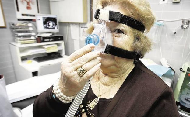 Una paciente se coloca una mascarilla para recibir oxígeno.