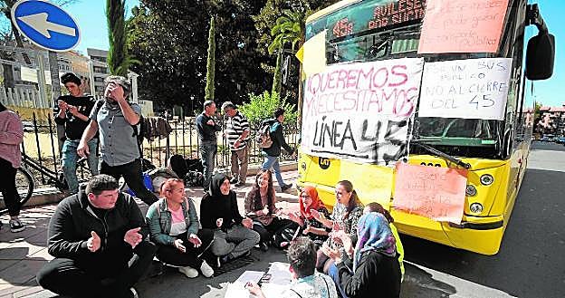 Usuarios de la línea 45, ayer, en la calle Proclamación, ante el bus que empapelaron.