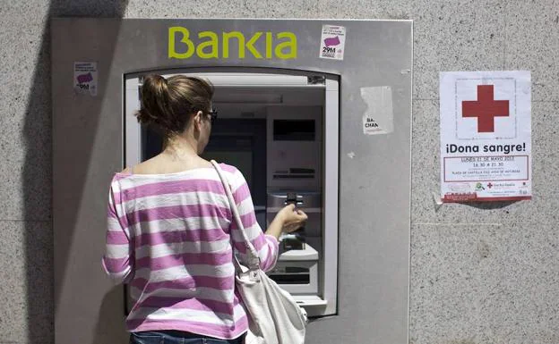 Una mujer utiliza un cajero automático de Bankia.