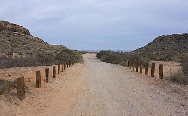 Camino de acceso a la playa de La Higuerica, delimitado por traviesas de madera.
