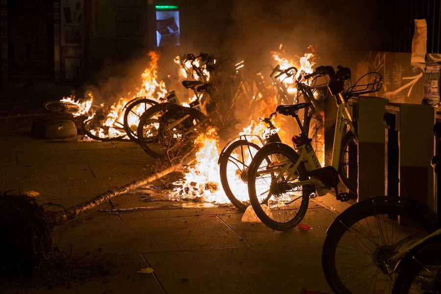 Un grupo de más de medio centenar de personas han quemado contenedores y causado desperfectos en el mobiliario urbano en el madrileño barrio de Lavapiés tras la muerte este jueves de un mantero de 35 años y origen subsahariano a causa de una parada cardiorrespiratoria.