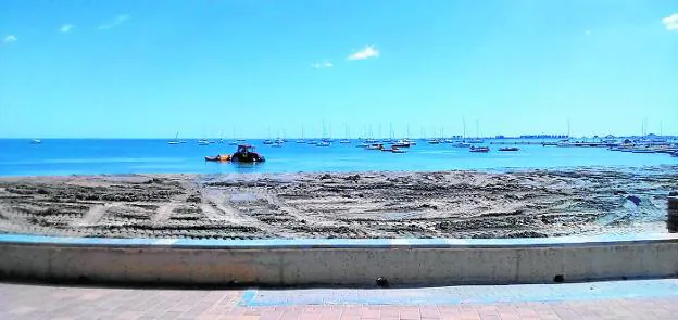 Un tractor circula dentro del agua arrastrando arena con una traílla en la playa de Colón (Santiago de la Ribera). La fotografía se tomó esta semana.