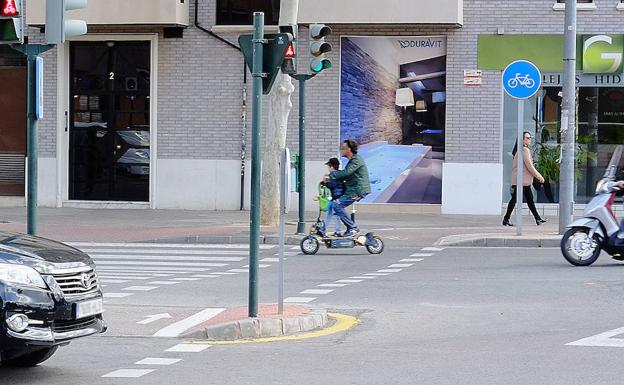 Un patinete eléctrico circula por la calzada en la avenida Príncipe de Asturias de Murcia con un niño a bordo. 