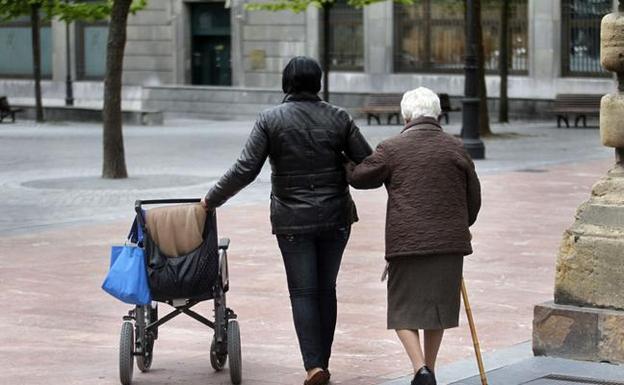 Una anciana se apoya en su acompañante para caminar. 