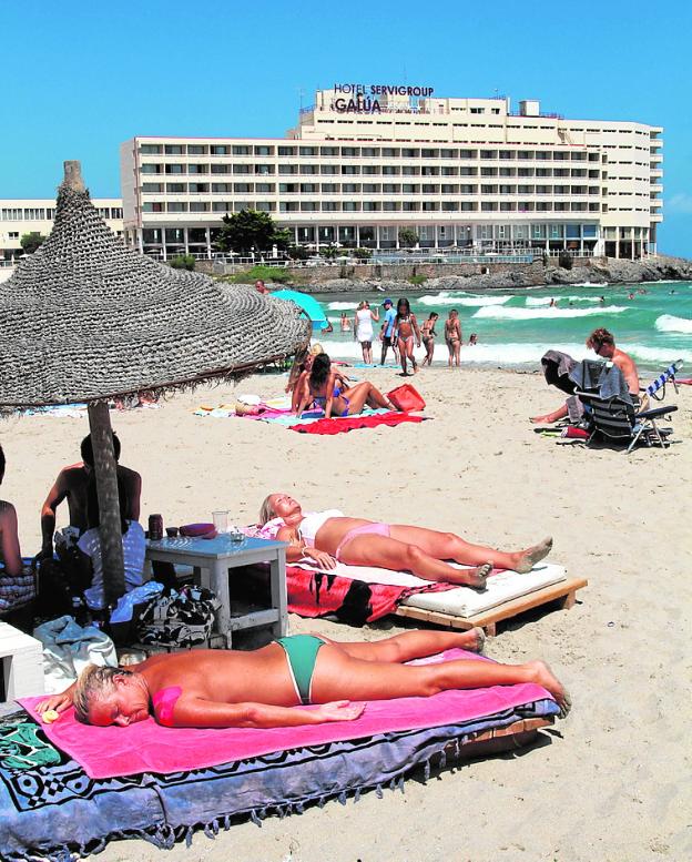 Turistas en una playa de La Manga, con el hotel Galúa al fondo. 
