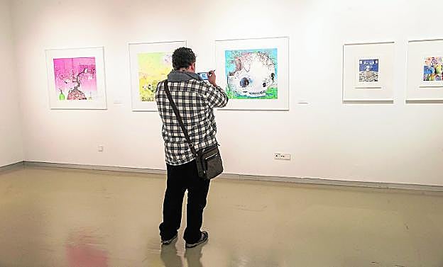 Un visitante fotografía algunas de las obras expuestas en el Muram.