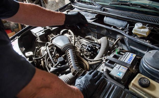 Un mecánico manipula el motor de un vehículo en un taller de Murcia.
