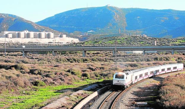 Arriba, un tren por El Hondón, con la autovía detrás.