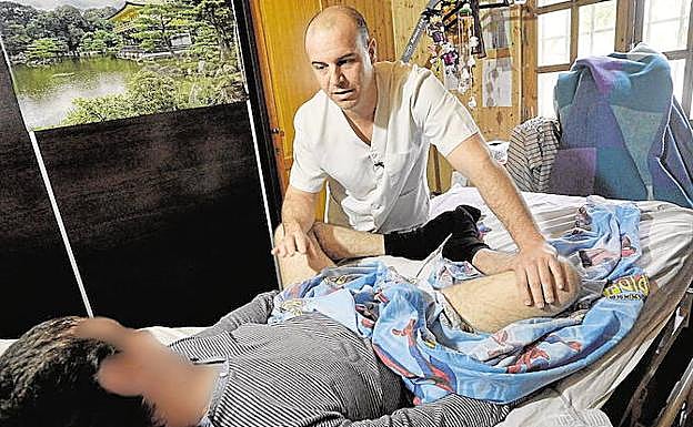 Iván Alcázar, flexionando las piernas de Alejandro para paliar los dolores, en una imagen de archivo.