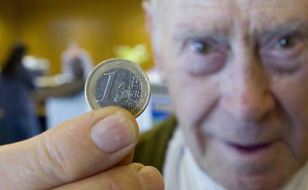 Un anciano de 82 años sostiene un euro. 