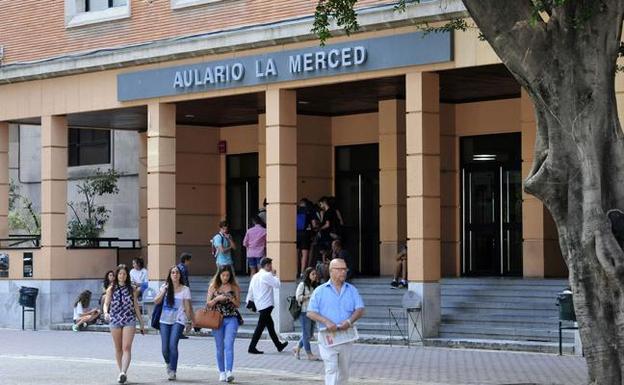 Varios estudiantes caminan frente al aulario de la Universidad de Murcia. 