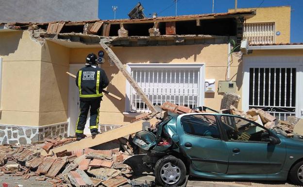 Un bombero trabaja para sanear la zona tras el derrumbe parcial en el edificio.