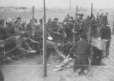 Imagen secundaria 1 - Barricada en París durante la Comuna, 1870-71 | Refugiados españoles en el campo de Saint Cyprien a la hora de la comida | No es la frontera entre México y Estados Unidos, es el campo de internamiento de Saint Cyprien en el Rosellón Francés en 1939. La alambrada separa a un padre de su mujer y sus hijos, internados en el campo para exiliados.