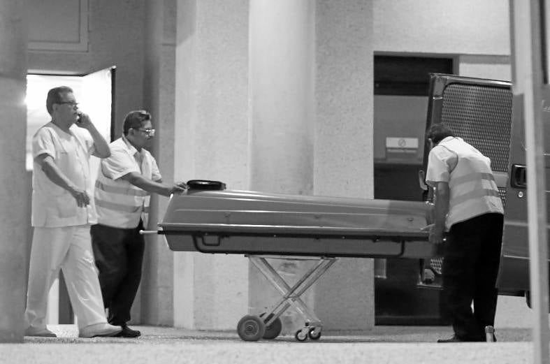 Los servicios de la funeraria trasladan el cuerpo. 