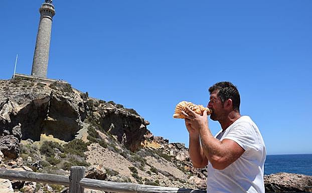El pescador cartagenero José María Méndez sopla su caracola frente al faro de Cabo de Palos.