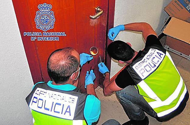 Dos especialistas de la Policía Nacional analizan una puerta. 