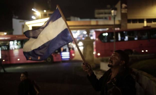 Un hombre sostiene una bandera de Nicaragua. 