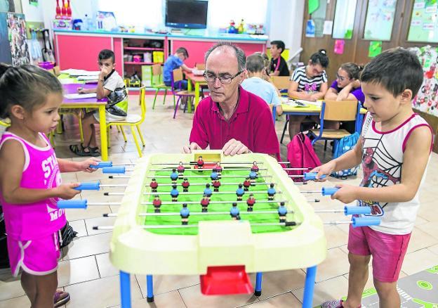 Juan Carlos Carrión observa a dos niños jugando en la sala de los más pequeños en la parroquia de Almanjáyar, en Granada. 