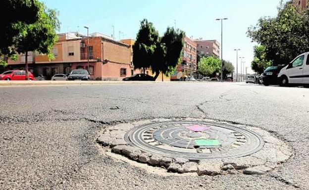 Una tapa de alcantarillado, rodeada de grietas en el asfalto, en la Avenida Ingeniero de la Cierva del Barrio de San Ginés. 