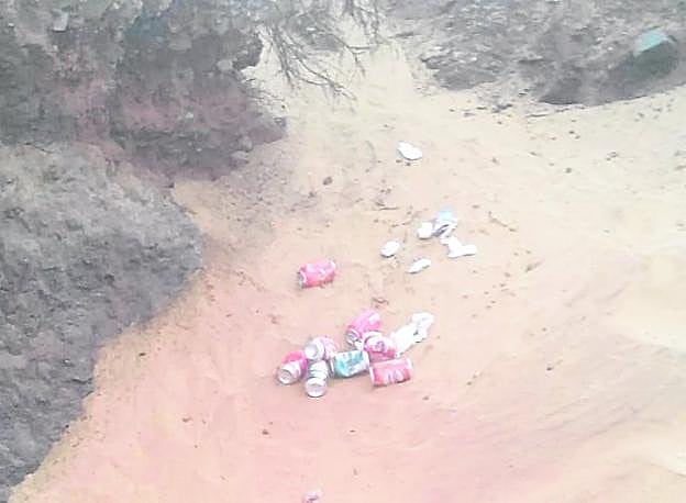 Unas latas, tiradas en una zona de arena de playa. 