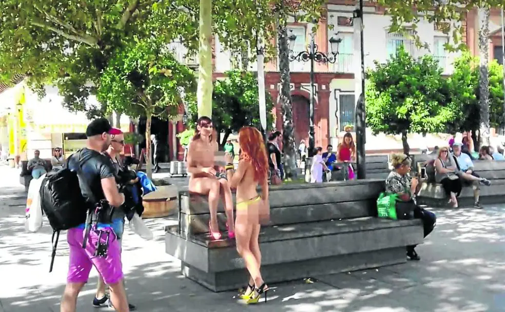 Dos actrices desnudas charlan en una pausa de un rodaje en una plaza sevillana. 