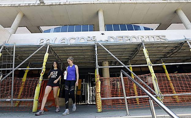 Usuarias del Palacio de Deportes, el pasado junio, abandonando la instalación municipal, protegida por andamios para evitar desprendimientos.
