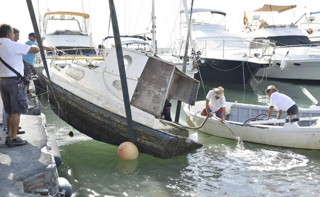 Los trabajos de extracción de una embarcación semihundida en el Mar Menor.