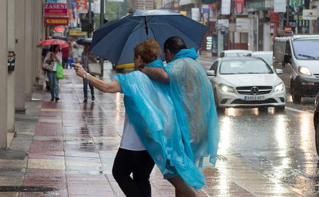 Una pareja se refugia de la lluvia en Murcia. (Archivo)