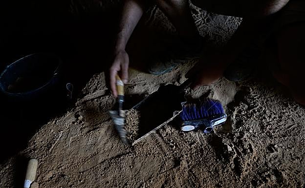 Un arqueólogo recoge con cuidado el sedimento para cribarlo . 