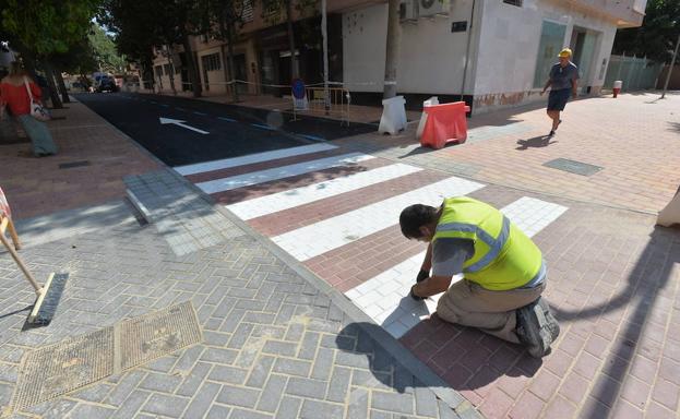 Un trabajador comienza a levantar los adoquines del paso de cebra mal pintado en una calle de Lorca.
