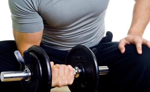 Un hombre practica deporte en un gimnasio. 