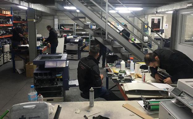 Unos trabajadores arreglan impresoras en el taller