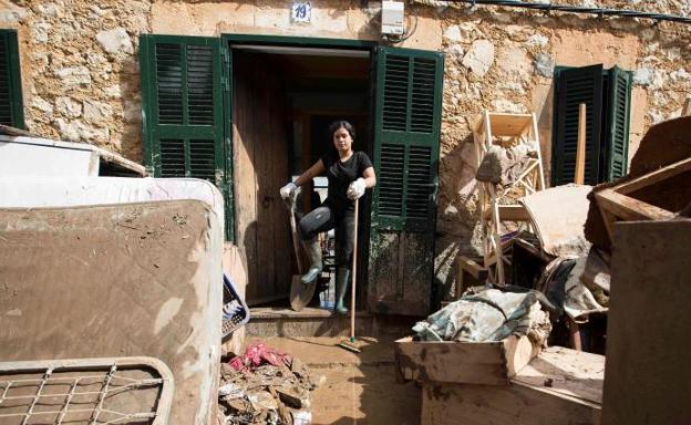 Una mujer achicha barro en su casa de Sant Llorenc des Cardassar.