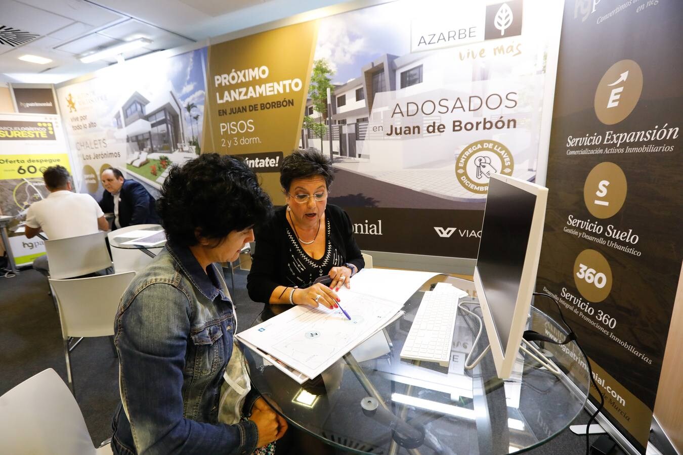Varios clientes son atendidos en expositores de promotoras en la feria inmobiliaria 'Reside 2018' en el Hotel NH Amistad