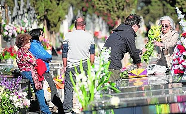 Rezos y muchos ramos de flores en el cementerio para honrar a los familiares fallecidos . 