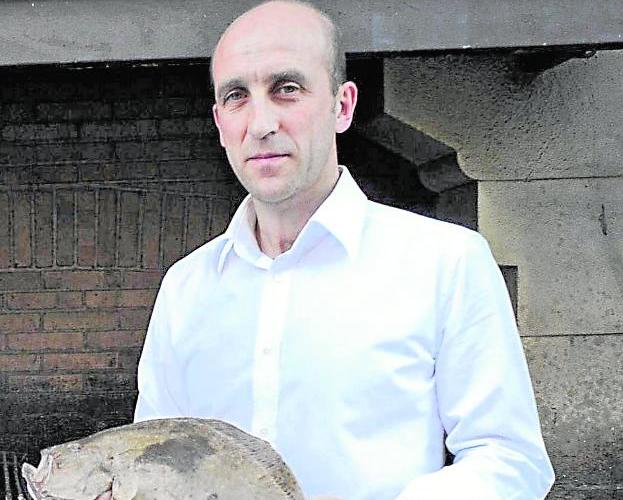 Aitor Arregi, propietario del restaurante ElKano, en Guetaria, con un rodaballo.
