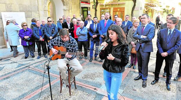 La artista murciana Farfett, acompañada por un guitarrista, interpreta una de sus canciones en la plaza de la Cruz de Murcia, donde se presentó el programa navideño. 