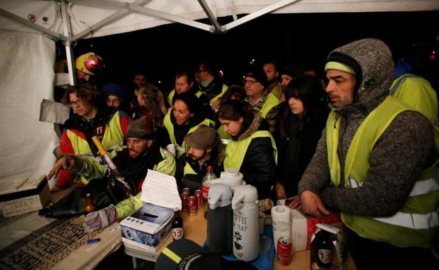 Manifestantes de los 'chalecos amarillos' escuchan el discurso de Macron.