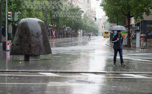 Un ciudadano pasea por la Gran Vía en un día de lluvia en la capital de la Región.