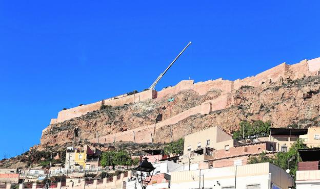 Una gran grúa se encarga de suspender la cesta de trabajo desde la que los operarios perforan el macizo rocoso del castillo. 