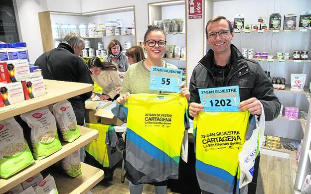 Dos participantes muestran su dorsal y su camiseta, ayer en la tienda de Marnys en la calle del Carmen. 