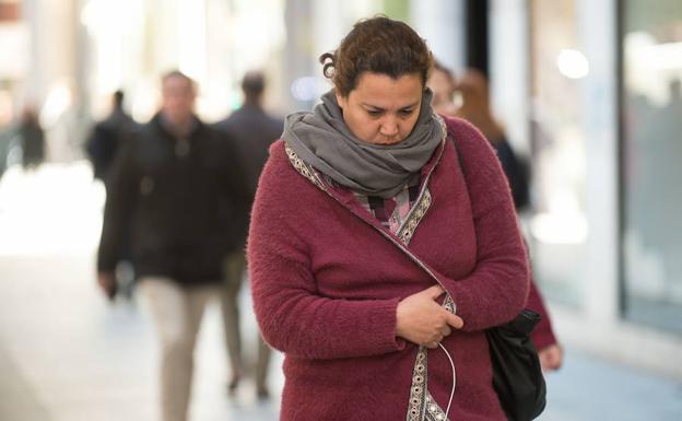 Una mujer, pasea abrigada por las calles de Murcia.