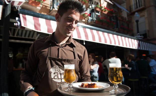 Un camarero sirve a unos clientes en una terraza de Murcia.