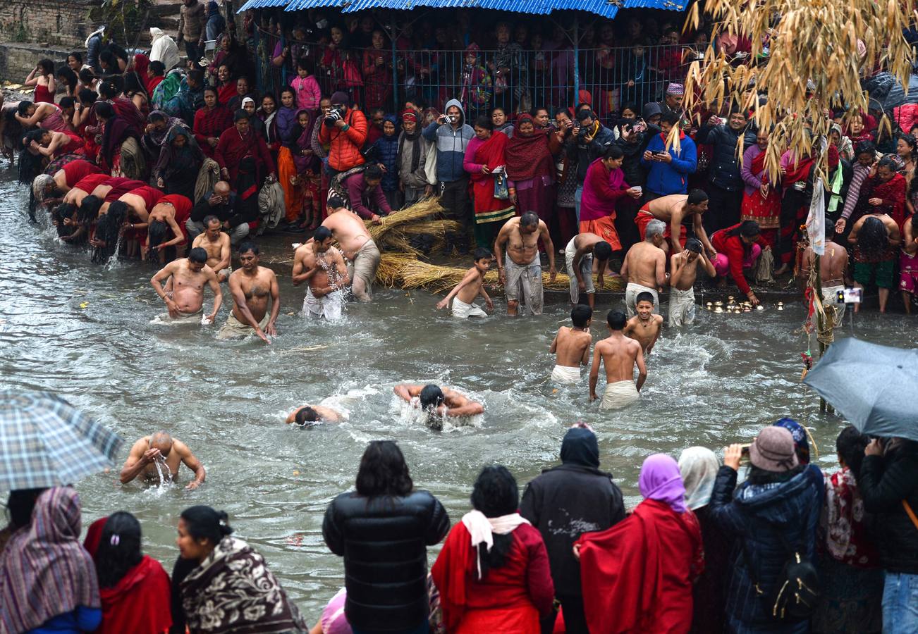 Devotos toman un baño sagrado en el río Hanumante durante el último día del Festival Madhav Narayan en Bhaktapur (Nepal). El Madhay Narayan se celebra durante un mes completo en el que se toman baños sagrados para lavar los pecados y se estudia el libro Swasthani. La veneración a la diosa Swasthani, una festividad que solo se conmemora en Nepal, es única en cada pueblo, con celebraciones y tradiciones diferentes.