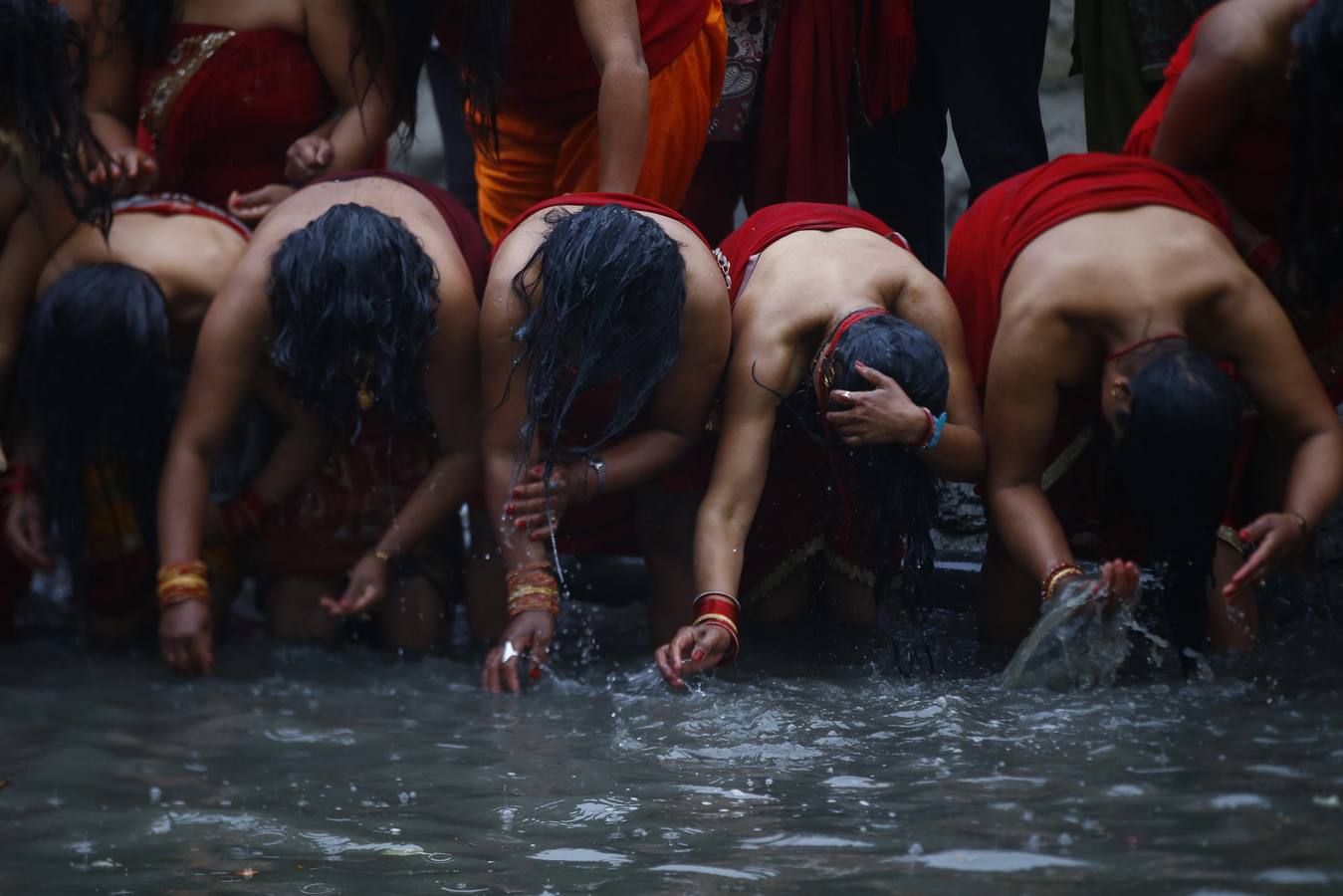 Devotos toman un baño sagrado en el río Hanumante durante el último día del Festival Madhav Narayan en Bhaktapur (Nepal). El Madhay Narayan se celebra durante un mes completo en el que se toman baños sagrados para lavar los pecados y se estudia el libro Swasthani. La veneración a la diosa Swasthani, una festividad que solo se conmemora en Nepal, es única en cada pueblo, con celebraciones y tradiciones diferentes.