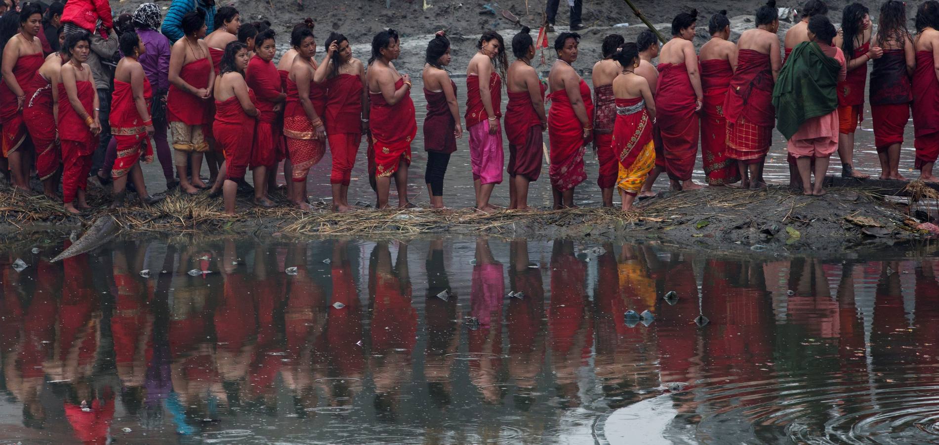 Devotos toman un baño sagrado en el río Hanumante durante el último día del Festival Madhav Narayan en Bhaktapur (Nepal). El Madhay Narayan se celebra durante un mes completo en el que se toman baños sagrados para lavar los pecados y se estudia el libro Swasthani. La veneración a la diosa Swasthani, una festividad que solo se conmemora en Nepal, es única en cada pueblo, con celebraciones y tradiciones diferentes.