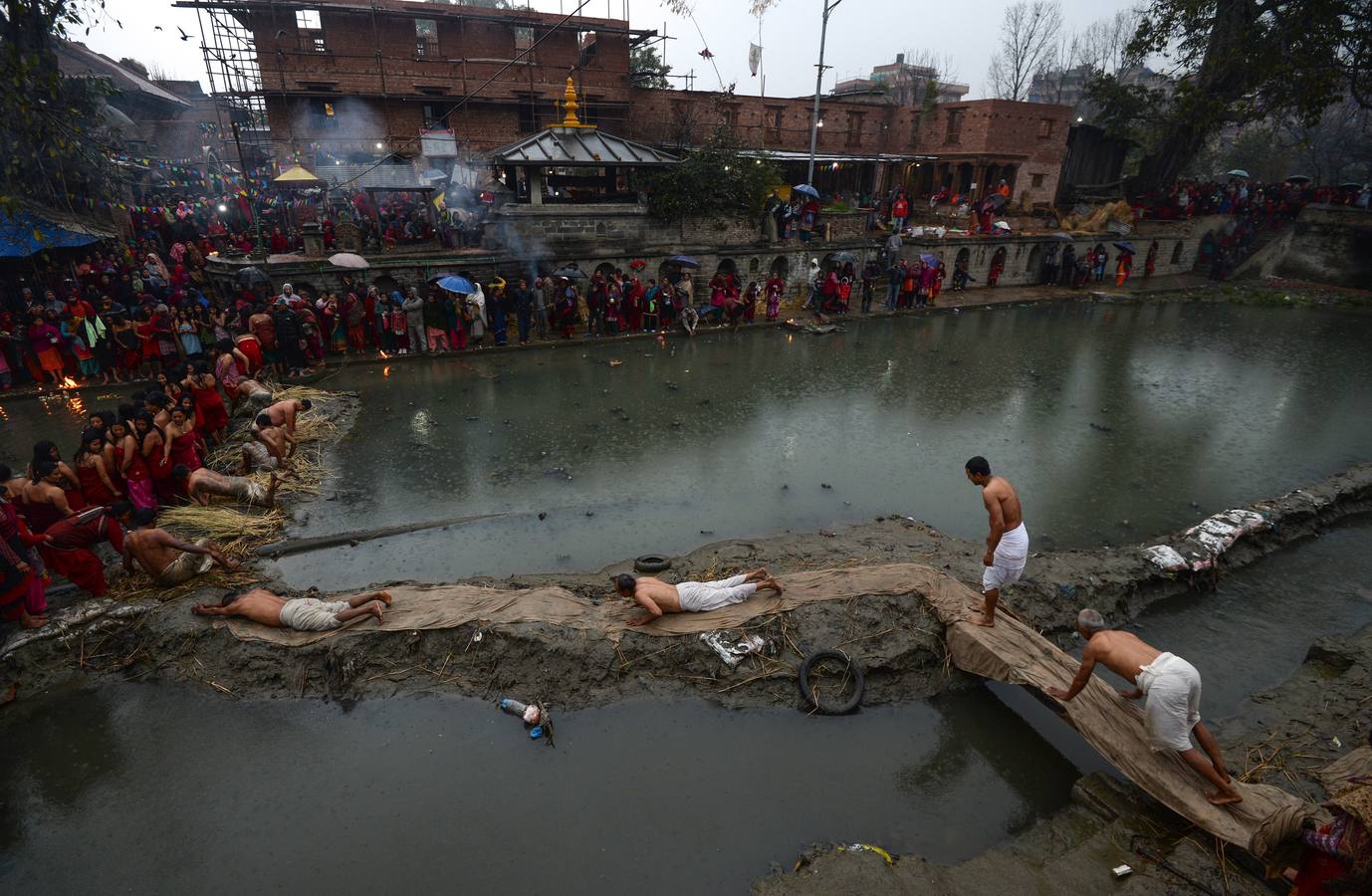 Devotos toman un baño sagrado en el río Hanumante durante el último día del Festival Madhav Narayan en Bhaktapur (Nepal). El Madhay Narayan se celebra durante un mes completo en el que se toman baños sagrados para lavar los pecados y se estudia el libro Swasthani. La veneración a la diosa Swasthani, una festividad que solo se conmemora en Nepal, es única en cada pueblo, con celebraciones y tradiciones diferentes.