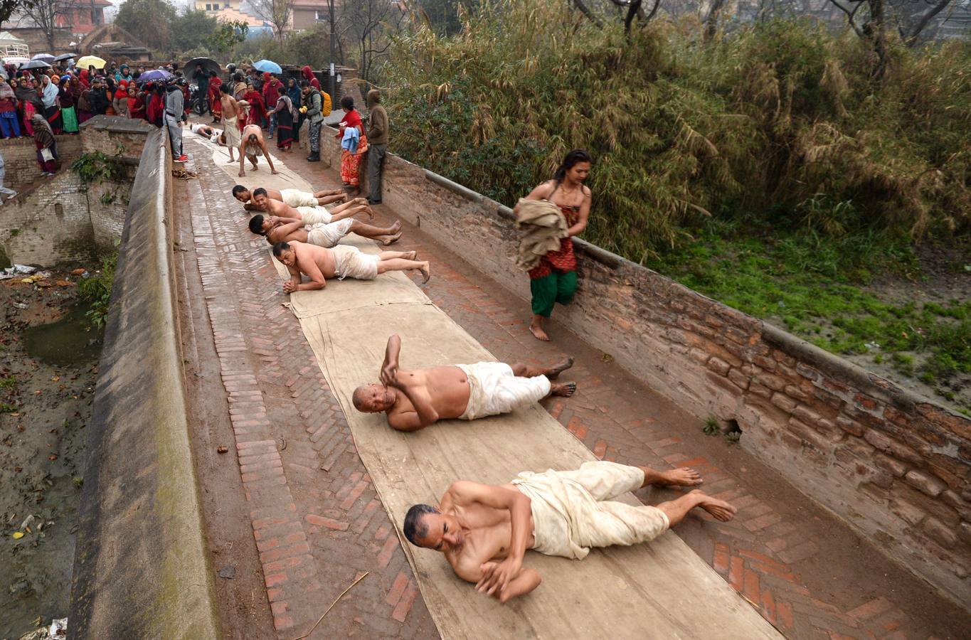 Devotos toman un baño sagrado en el río Hanumante durante el último día del Festival Madhav Narayan en Bhaktapur (Nepal). El Madhay Narayan se celebra durante un mes completo en el que se toman baños sagrados para lavar los pecados y se estudia el libro Swasthani. La veneración a la diosa Swasthani, una festividad que solo se conmemora en Nepal, es única en cada pueblo, con celebraciones y tradiciones diferentes.