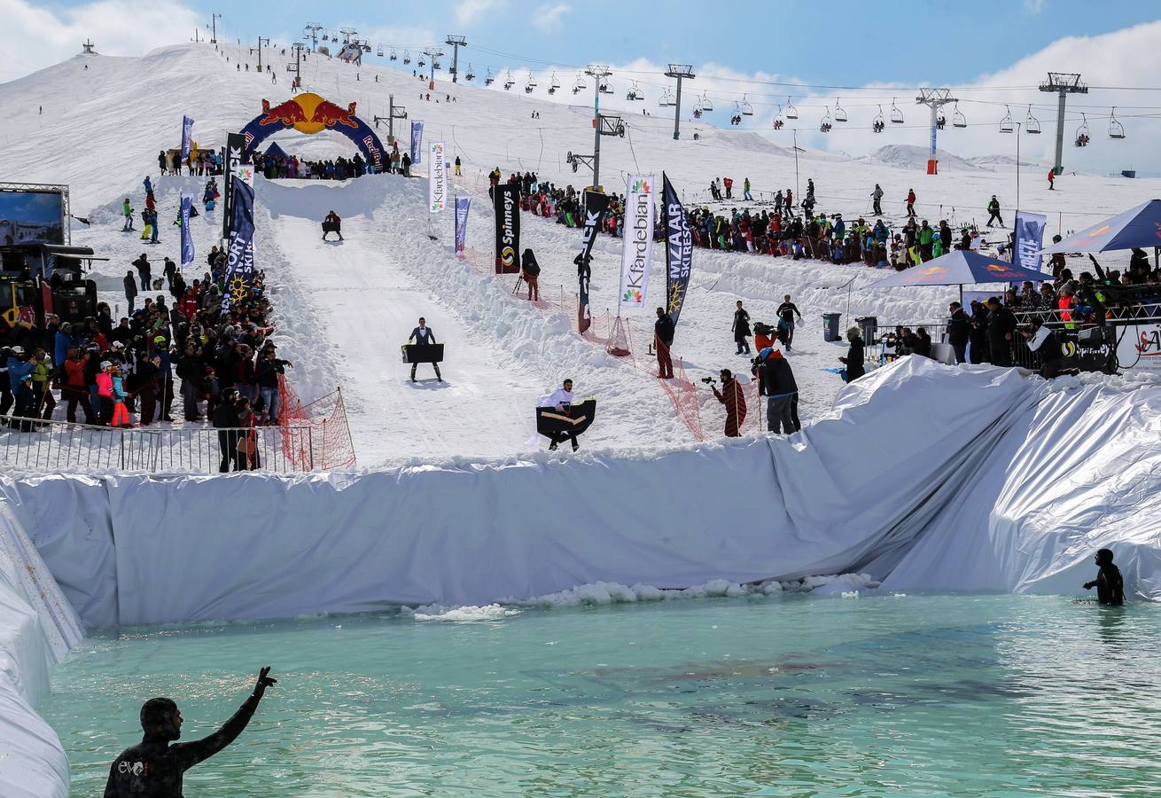 Varios participantes participan en competención Red Bull Jump and Freeze en la estación de esquí Mzaar en Kfardebian Lebanon Mountain, en Kfardebian, Líbano. Los participantes que usan trajes festivos realizan piruetas antes de meterse en un estanque con agua helada. 