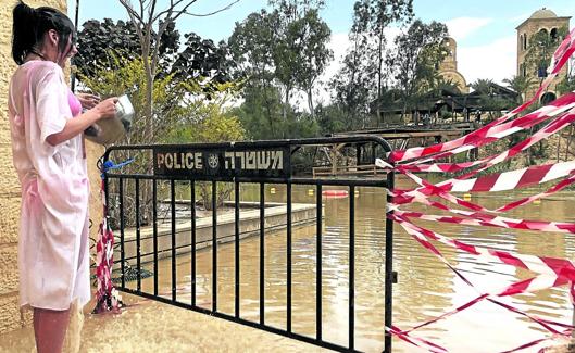 Una peregrina se purifica en la orilla del Jordán, cuyo acceso en Qasr el Yahud ha sido vallado por la Policía para impedir el paso hacia aguas más profundas. 
